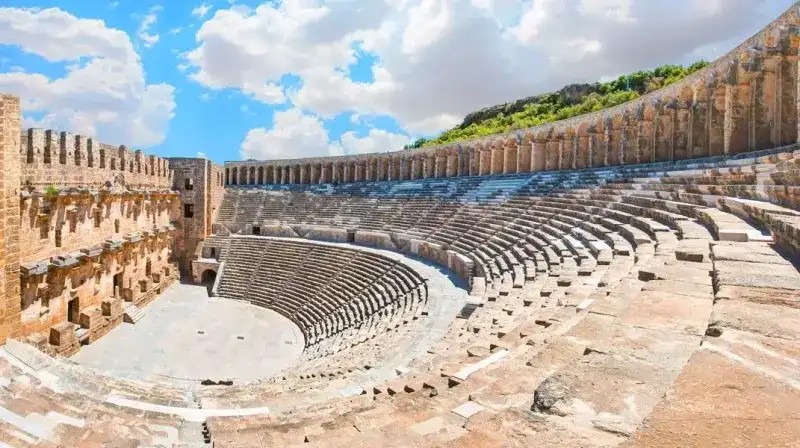 <p><strong>4. Balık Ekmek ve Sahil Keyfi</strong></p>
<p>Kaleiçi Yat Limanı, Antalya Balıkçı Barınağı ve falez manzaralı çay bahçeleri… Antalyalılar için balık ekmek yemek, ardından deniz kenarında çay içmek küçük ama paha biçilemez bir keyiftir. Özellikle hafta sonları bu alanlar dolup taşar.</p>
<p><strong>5. Pazardan Alışveriş Yapmak</strong></p>
<p>Antalyalılar süpermarketten alışveriş yapar ama asıl keyif, yerel pazarları gezmekte. Salı Pazarı, Cuma Pazarı, Çarşamba Muratpaşa Pazarı gibi yerler, taze ürünlerin, samimi sohbetlerin ve renkli görüntülerin adresidir. Pazarda meyve tadarak alışveriş yapmak bile ayrı bir zevktir.</p>
<p><strong>6. Günübirlik Tekne Turlarına Katılmak</strong></p>
<p>Hafta sonunu farklı bir şekilde değerlendirmek isteyen Antalyalıların ilk tercihlerinden biri günübirlik tekne turları. Kemer, Adrasan ya da Kaş'tan hareket eden bu teknelerle koy koy gezmek, denize atlamak ve güneşlenmek halkın yaz ritüellerinden biridir.</p>
<p><strong>7. Akşam Üzeri Sahilde Tavla Oynamak</strong></p>
<p>Lara plajının ve falez parklarının banklarında, Konyaaltı sahilinin çay bahçelerinde akşam üzeri tavla sesleri eksik olmaz. Antalyalılar için dostlarla tavla oynamak, deniz havası eşliğinde günün stresini atmanın en güzel yollarındandır.</p>
<p><strong>8. Yılın Her Zamanı Dondurma Yemek</strong></p>
<p>Antalya’da yaz kış dondurma tüketilir. Şehir halkı dondurmayı sadece sıcak havada değil, bazen yağmurlu bir kış gününde bile yemeyi sever. Özellikle yerel üretim yapan butik dondurmacılar, Antalyalıların uğrak noktalarındandır.</p>
<p><strong>9. Tarihi Yerlerde Zaman Geçirmek</strong></p>
<p>Aspendos, Termessos, Perge, Olympos gibi antik kentler, sadece turistler için değil, Antalyalılar için de bir nefes alma alanıdır. Tarihle iç içe piknik yapmak, çocuklara geçmişi göstermek ya da sessizce yürüyüş yapmak burada yaşayanlar için özel bir deneyimdir.</p>
<p><strong>10. Kendi Bahçesinde Ürün Yetiştirmek</strong></p>
<p>Antalya ikliminin sunduğu bereketten yararlanmayı bilen Antalyalılar, özellikle şehir merkezinden biraz uzakta yaşayanlar, kendi limonunu, domatesini, narını yetiştirmeyi sever. Bu uğraş sadece üretim değil, aynı zamanda bir terapi biçimidir.</p>